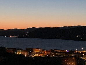 A coastal cityscape at dusk with buildings along the waterfront and hills in the background. - Large studio with stunning sea view for breakfast and 5 minutes from the beach (Propriano)