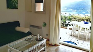 Ein Wohnzimmer mit einer Couch, einem Couchtisch und Blick auf eine Terrasse mit Tisch und Stühlen.