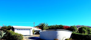 Surrounded by lush greenery, this property offers a serene escape with an entrance and a driveway leading to a garage.