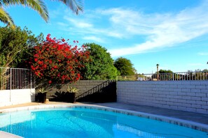Relax by the serene pool surrounded by lush greenery and vibrant flowers.
