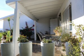 Relax on the patio with a metal table and comfortable seating, surrounded by lush potted plants.