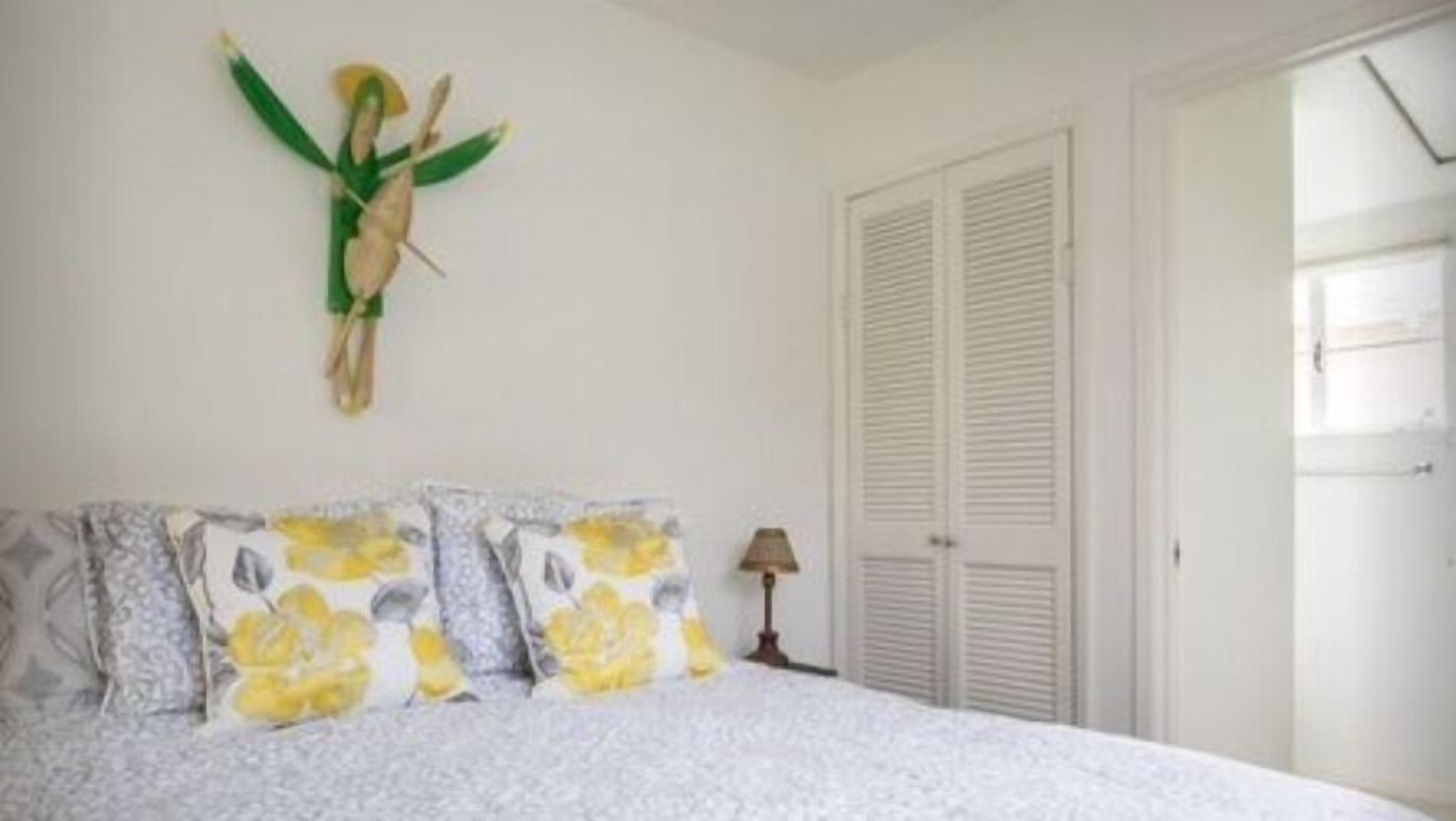 A bedroom with a bed, pillows, a lamp, and a door.