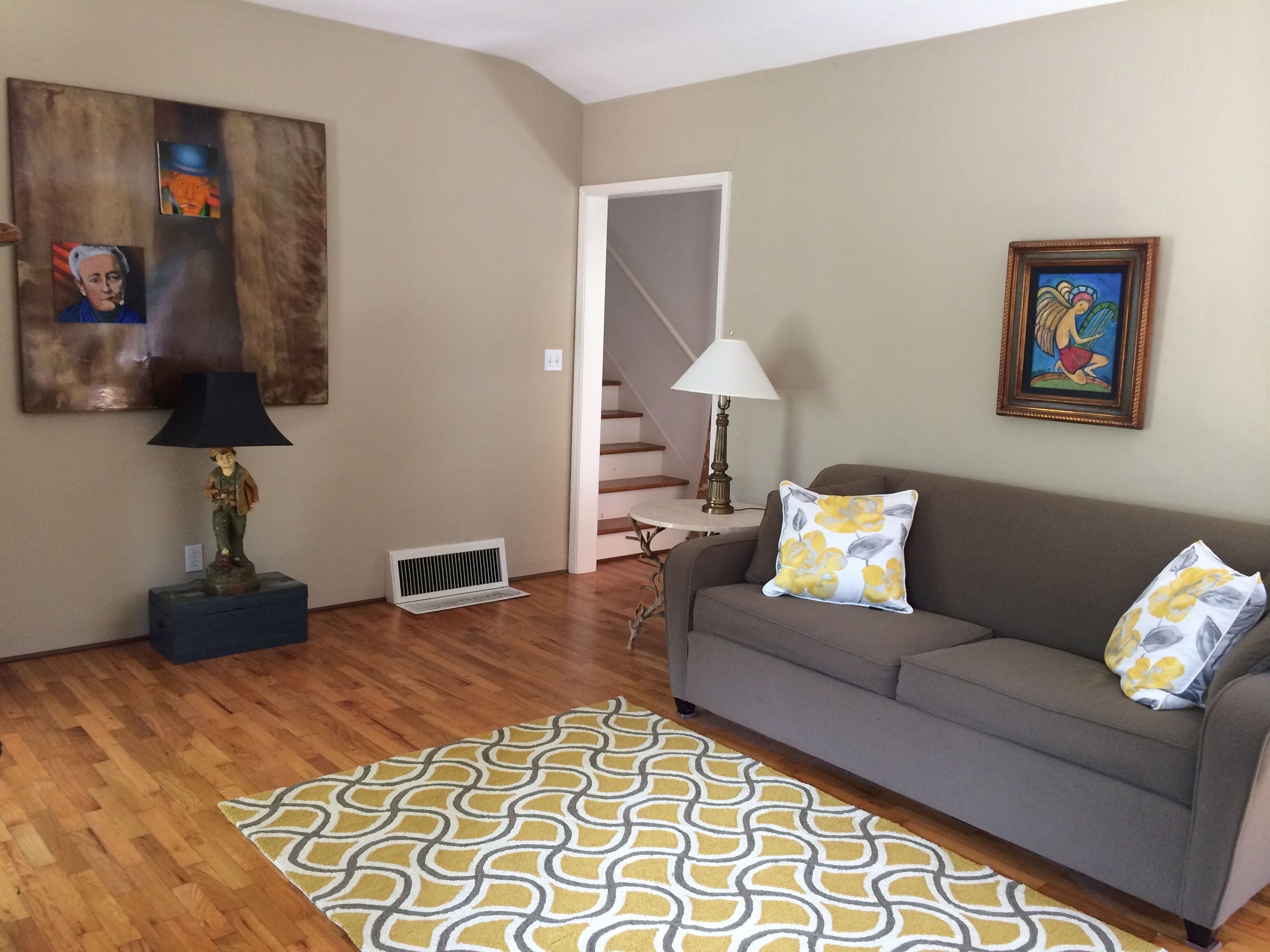 A living room with a sofa, patterned rug, and artwork on the walls.