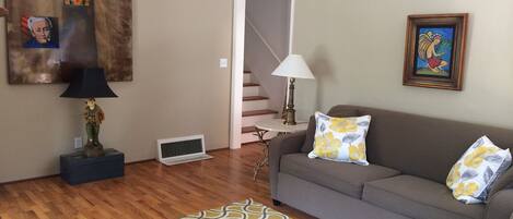 A living room with a sofa, patterned rug, and artwork on the walls.