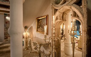 Een decoratieve kamer met een grote spiegel, een lijstwerk schilderij en een tafel met kandelaars.