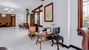 A spacious room with a dining area, a computer desk, and a large window. - OYO 512 Ndalem Mantrijeron Hotel (Yogyakarta)