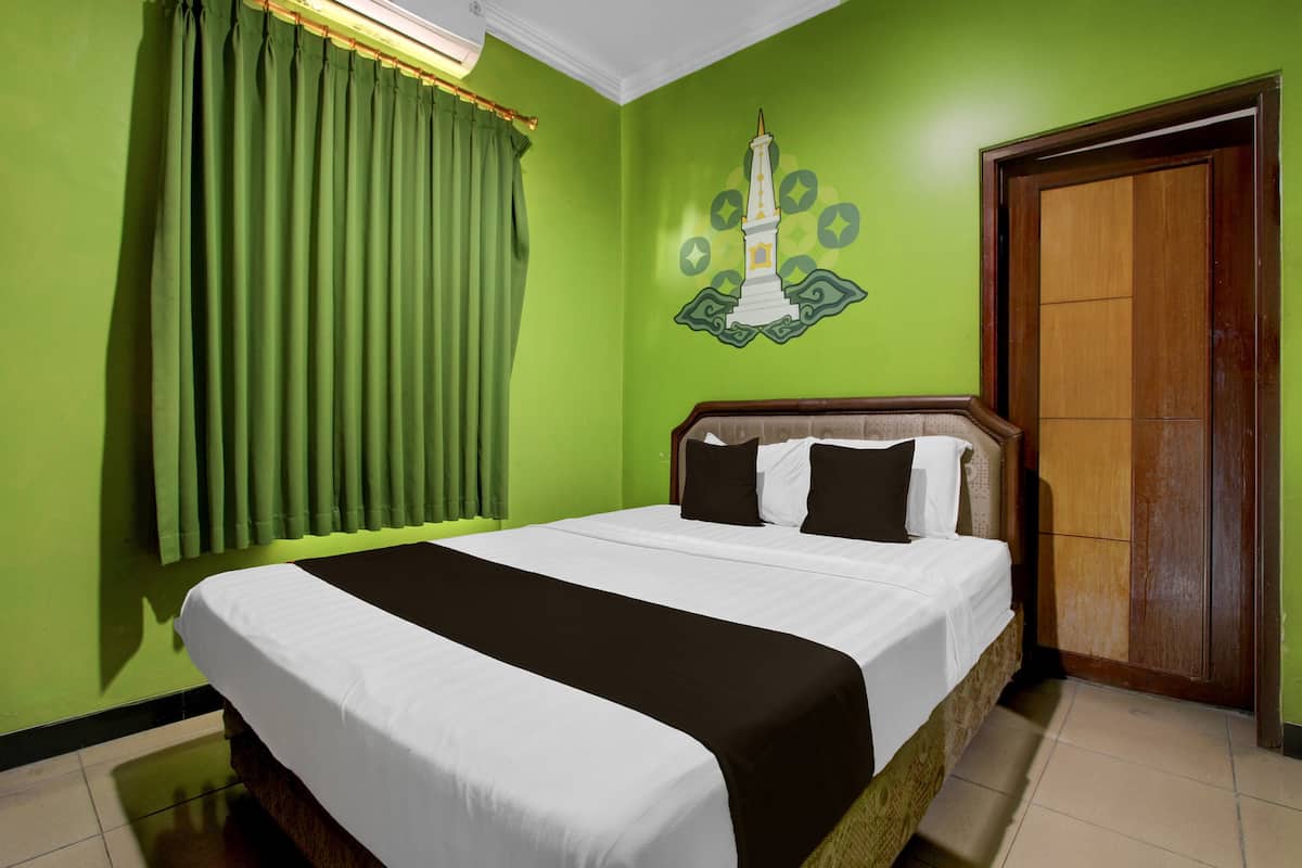Quarto de hotel com uma cama, cortinas verdes, uma porta de madeira e um mural na parede.