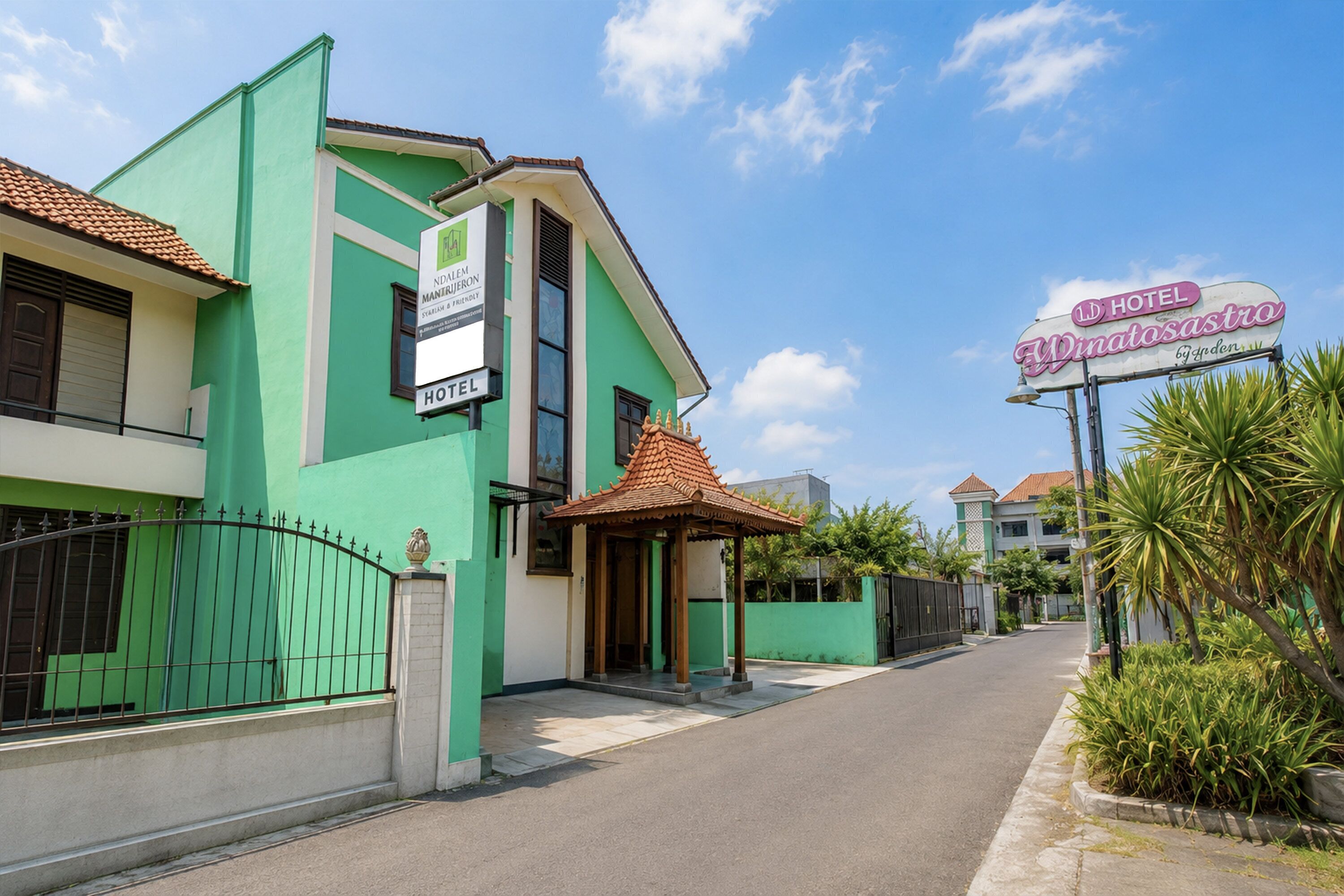 A green building with a sign indicating it's a hotel, a covered entrance, and a street view.