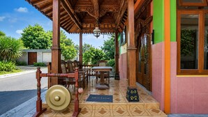 A traditional wooden structure with a tiled entrance, a welcome mat, and a table with chairs outside. - OYO 512 Ndalem Mantrijeron Hotel (Yogyakarta)