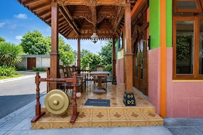 Una estructura de madera tradicional con entrada de tejas, felpudo y mesa con sillas afuera.