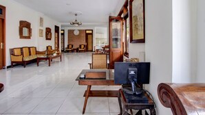 A spacious living room with a sofa, a coffee table, a TV, and a dining area in the background. - OYO 512 Ndalem Mantrijeron Hotel (Yogyakarta)