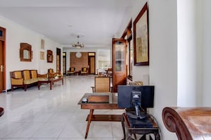 Amplia sala de estar con un sofá, una mesa de centro, un televisor y un área de comedor al fondo.