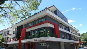 A hotel with a modern design, featuring a flat roof, large windows, and a red accent on the facade.