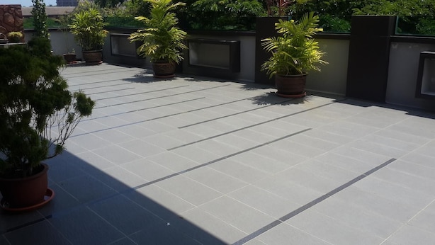 A rooftop terrace with potted plants and a tiled floor.