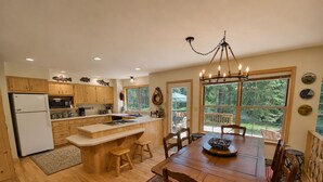 Una cucina con mobili in legno, un frigorifero, un tavolo da pranzo con sedie e un lampadario.