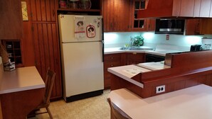 A compact kitchen with wooden cabinets, a white refrigerator, a microwave, and a sink. - Log cabin nestled beside Chiques Creek in historic Lancaster County (Mount Joy)