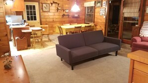 A cozy cabin interior with a dining area, a sofa, and a kitchen. - Log cabin nestled beside Chiques Creek in historic Lancaster County (Mount Joy)