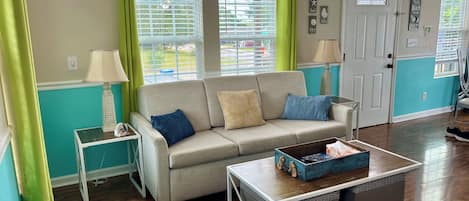 A living room with a beige sofa, two side tables, a coffee table, and a door.