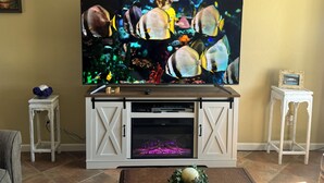 Un televisor montado en un mueble blanco con reproductor de DVD incorporado y un pequeño acuario debajo.