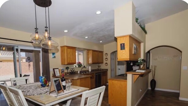 Una cocina moderna con armarios de madera, una zona de comedor con sillas blancas y una isla integrada.