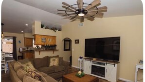 Una sala de estar con un sofá, televisor y ventilador de techo.