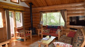 Interior acogedor de una cabaña de troncos con chimenea, muebles de madera y un televisor.