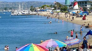 A beach with boats, a lighthouse, and a flag. - LUX Beachfront Casa de Balboa 231 w/AC - Best View (Newport Beach)