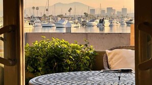 A view of a marina with boats, a city skyline, and a table with a cushion. - LUX Beachfront Casa de Balboa 231 w/AC - Best View (Newport Beach)