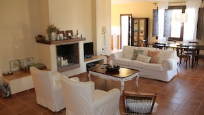 A spacious living room with a fireplace, white furniture, and a dining area with wooden chairs and a table. - Rural villa in Marrucho Alto (Riogordo)