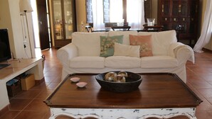 A living room with a white sofa, a wooden coffee table with decorative items, and a television on a stand. - Rural villa in Marrucho Alto (Riogordo)