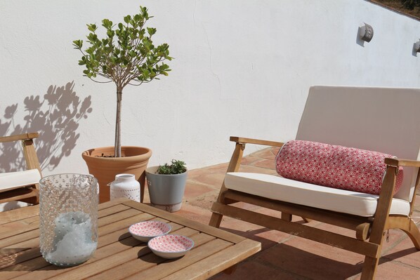 A wooden outdoor seating area with a white cushioned chair and a small potted plant. - Rural villa in Marrucho Alto (Riogordo)