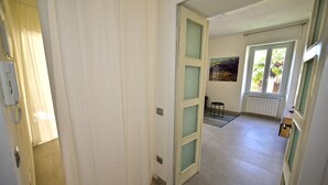 Ein Flur mit einer Tür zu einem Zimmer mit Fenster und Heizkörper.