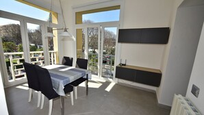 Ein Essbereich mit Tisch und Stühlen, einer Pendelleuchte, Blick durch große Fenster und einer integrierten Ablagefläche.