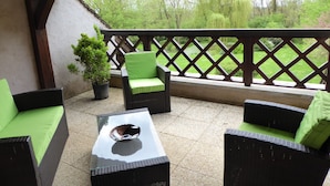 Un espace extérieur aménagé en terrasse, avec des meubles en osier et une table en verre, offrant une vue sur un paysage verdoyant.