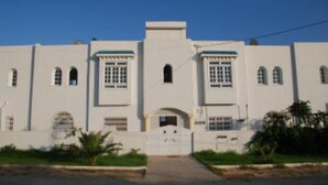 A white building with a central entrance, multiple windows, and a flat roof. - Apartment with sea view (Hammamet)