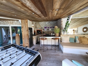 Una cucina accogliente con parete in pietra, soffitto in legno e tavolo da calcio.