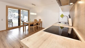Una cocina moderna con estufa integrada, mesa de comedor de madera y sillas.