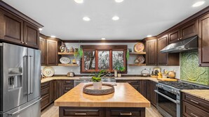 Una cocina moderna con gabinetes de madera oscura, electrodomésticos de acero inoxidable y una isla central con una planta en maceta.