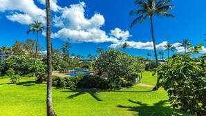 A lush green landscape with a swimming pool, palm trees, and a clear blue sky. - Remodeled!! Koa Resort #5J 2-Bd 2-Ba, A/C, South Maui, Walk To 3 Beaches! (Kihei)