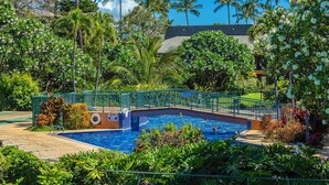 A swimming pool with a bridge, surrounded by lush greenery and palm trees. - Remodeled!! Koa Resort #5J 2-Bd 2-Ba, A/C, South Maui, Walk To 3 Beaches! (Kihei)