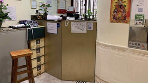 A reception area with a desk, a phone, and various notices on the wall. - Lucky Guest House (Kowloon)