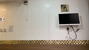 A wall-mounted TV, a fan, a no-smoking sign, and a QR code. - Lucky Guest House (Kowloon)