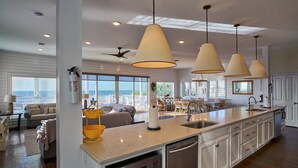 A spacious kitchen with a large island, pendant lighting, and a view to the outside.