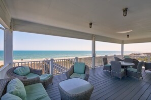 A covered deck with wicker furniture and a view of the ocean. - The Pineapple Beach Club (Ocean Isle Beach)