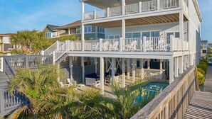 A multi-level beachfront property with a covered deck, outdoor seating, and a pool.