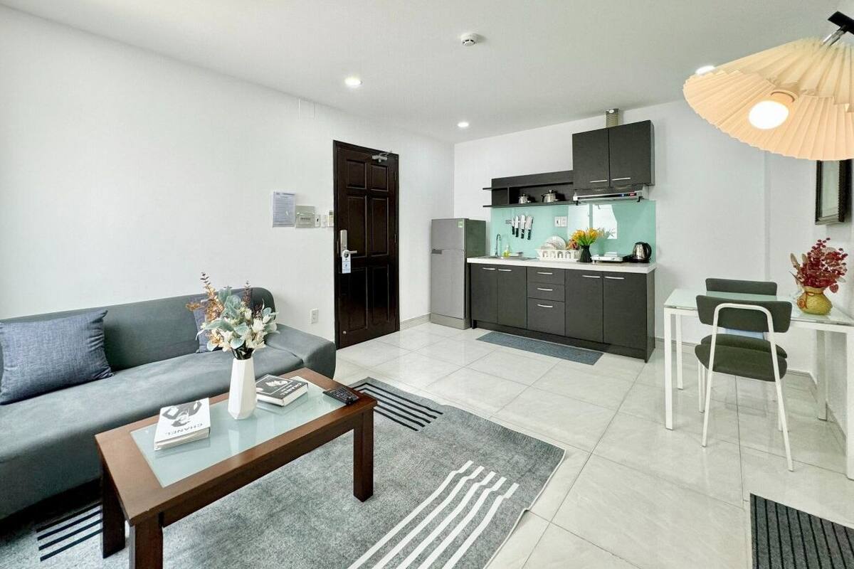 Un salon moderne avec un canapé gris, une table basse et un coin repas comprenant une table et des chaises blanches.