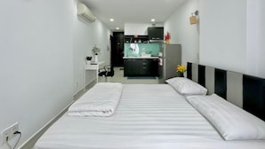 A hotel room with a bed, a desk, and a kitchenette. - Sabay Airport Apartment (Ho Chi Minh City)
