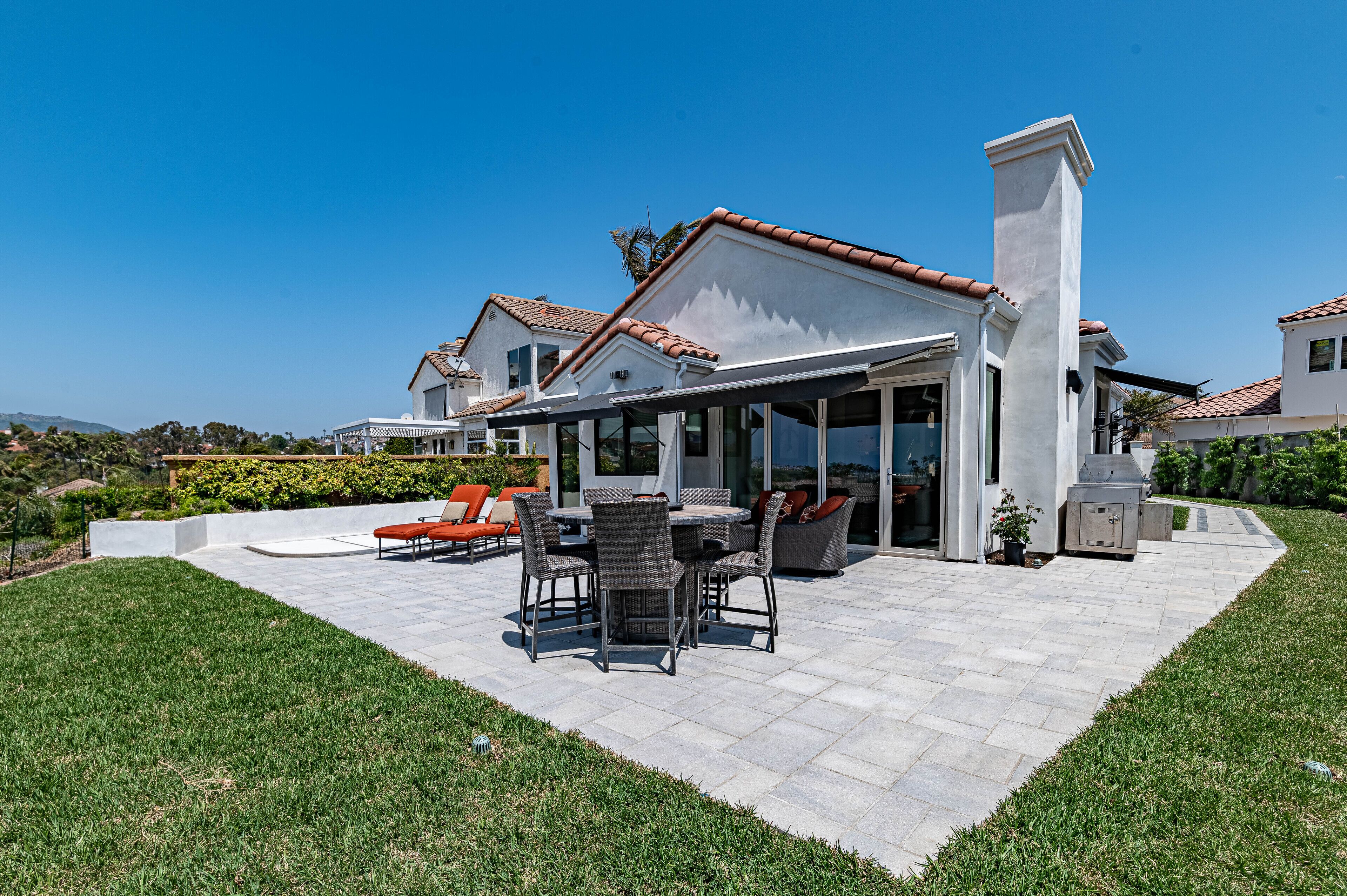 Un patio amplio con zona de comedor, mobiliario exterior y una chimenea grande.