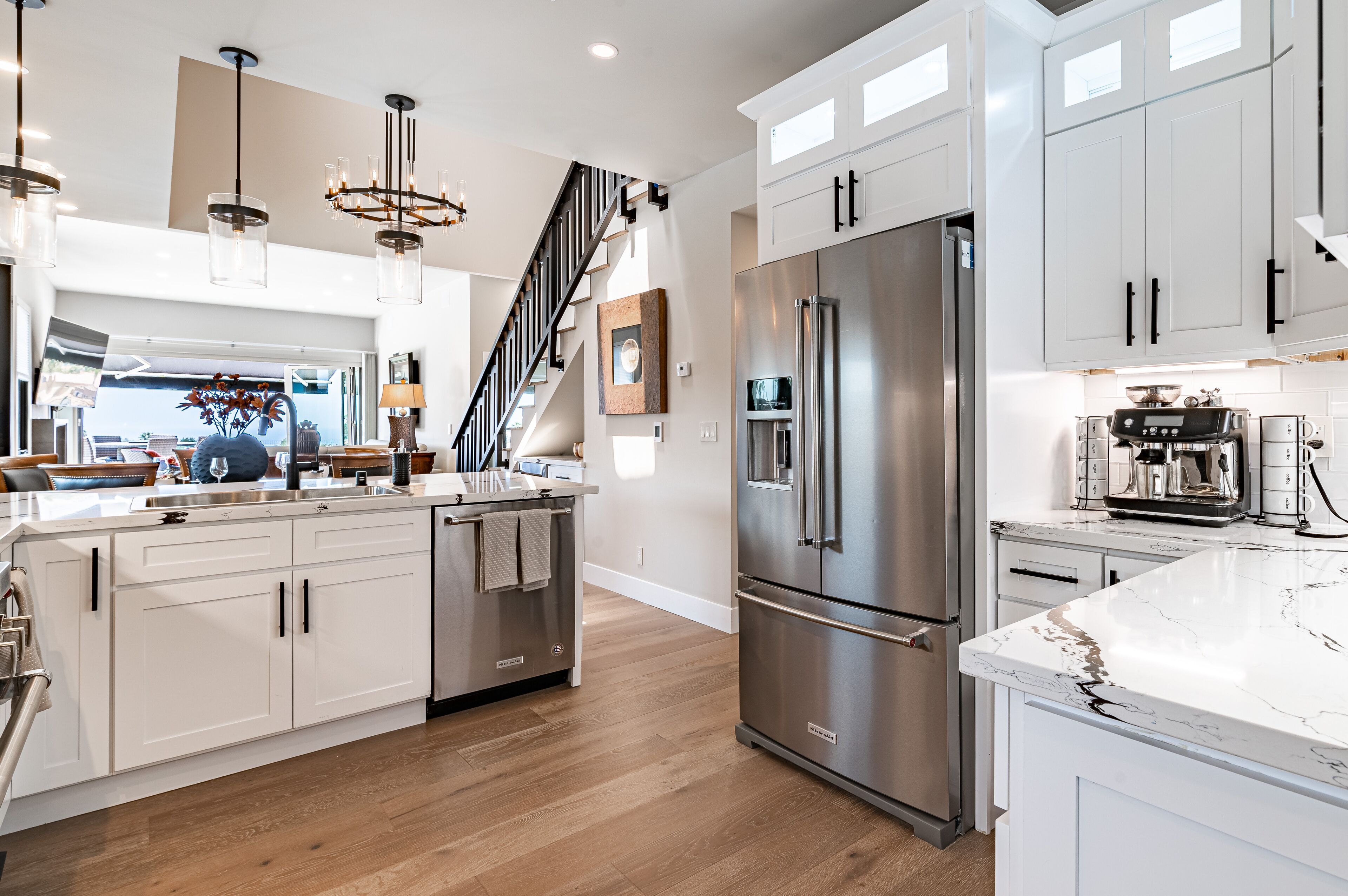 A modern kitchen with white cabinets, stainless steel appliances, and a marble countertop.