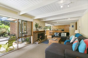 A spacious living area with a fireplace, a sofa set, a dining area, and a view of the outdoors. - Charlton House (Aireys Inlet)